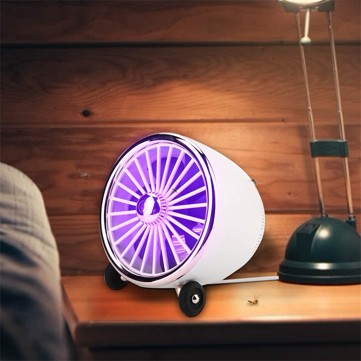 Weiße Insektenfalle mit lila Licht. Lampe und Tisch im Hintergrund. Insekten vorhanden.