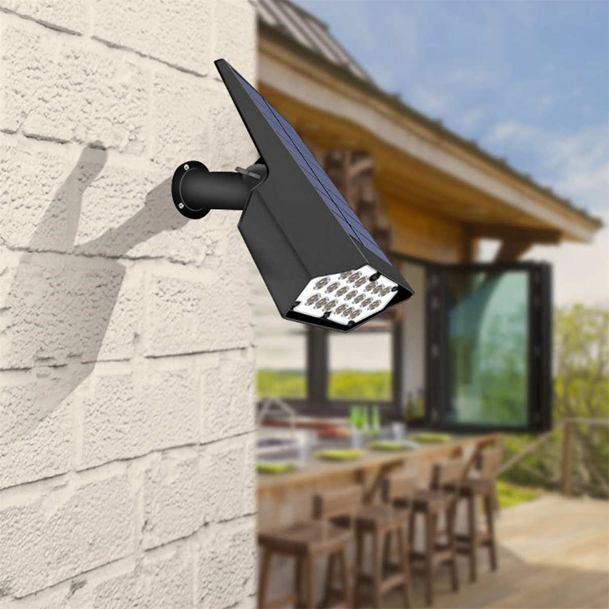 Eine schwarze Solarlampe an einer Ziegelmauer, mit einem Hintergrund aus Haus und Bäumen.