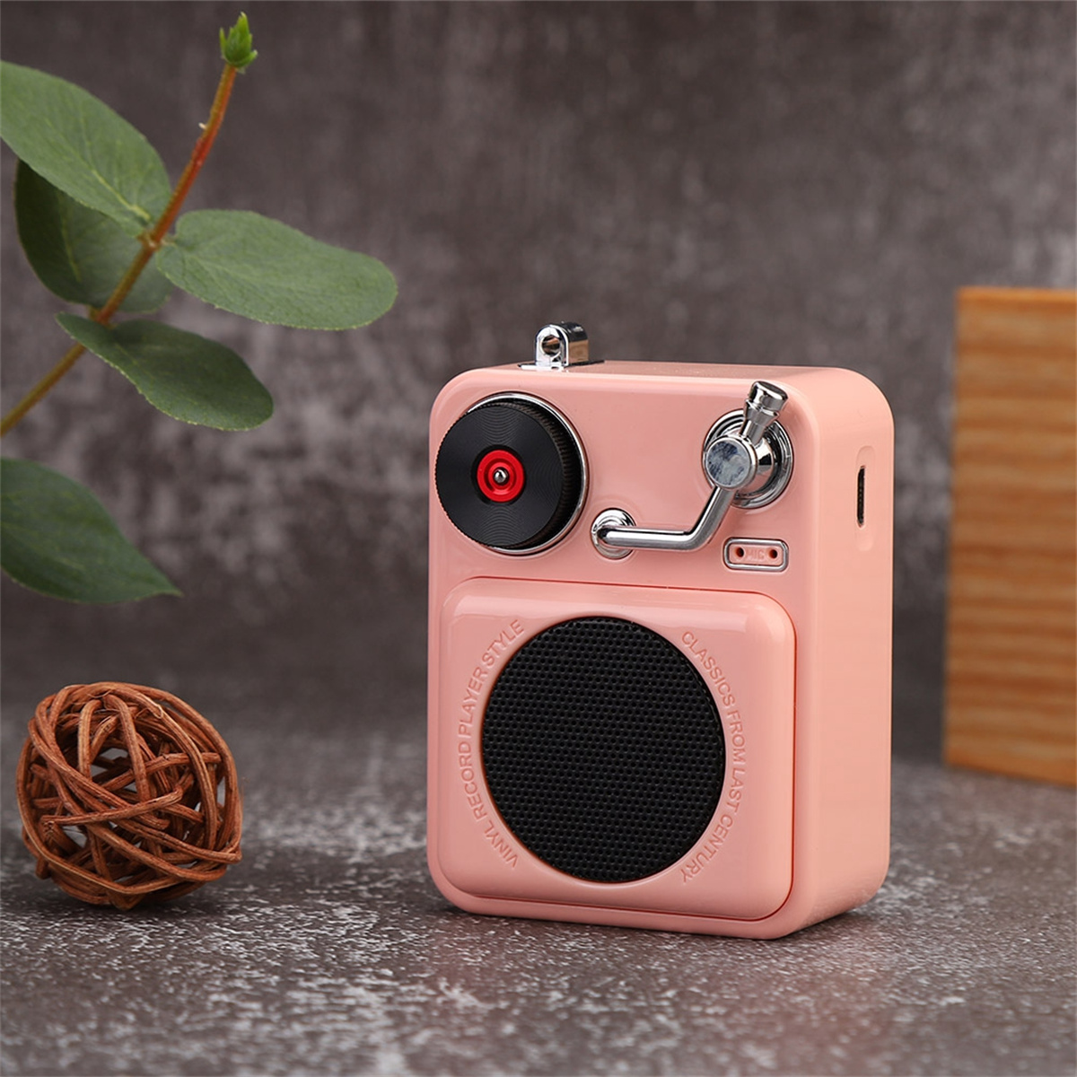 Ein rosa Radio im Retro-Stil mit Lautsprecher, Drehknopf und kleinem Plattenspieler.