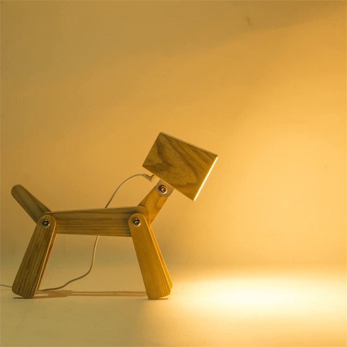 Eine holzfarbene, hundeförmige Lampe. Sie hat einen quadratischen Kopf, aus dem Licht scheint. Der Hintergrund ist beige.