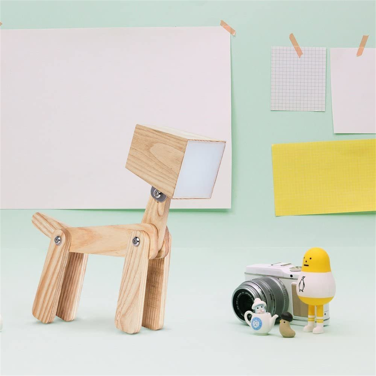 Hundelampe aus Holz. Eine Kamera, ein kleiner Pinguin, eine kleine Teekanne und eine kleine Figur daneben.