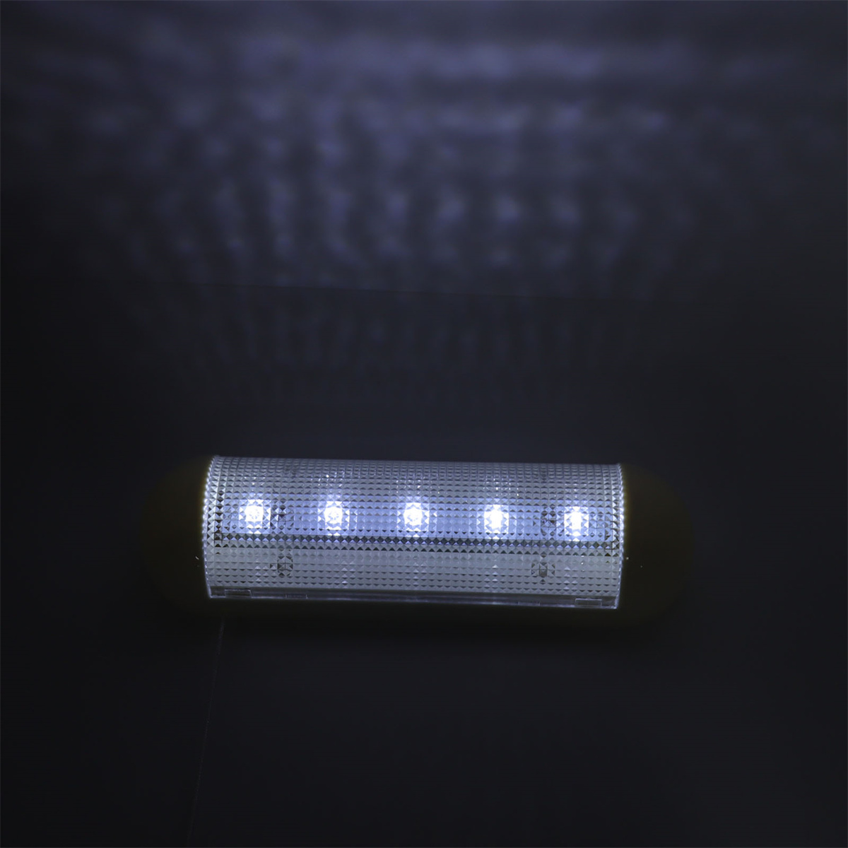 Eine rechteckige LED-Leuchte mit 5 leuchtenden LEDs. Vor einem dunklen Hintergrund.