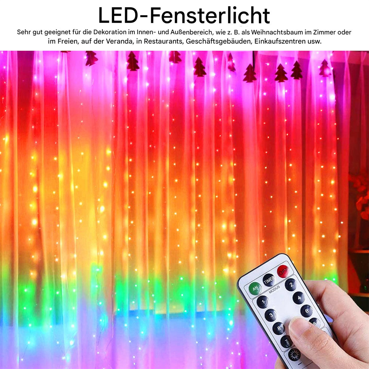 Eine Hand hält eine Fernbedienung und beleuchtet bunte LED-Lichter, die als Fenstervorhang mit Weihnachtsbäumen aufgebaut sind.