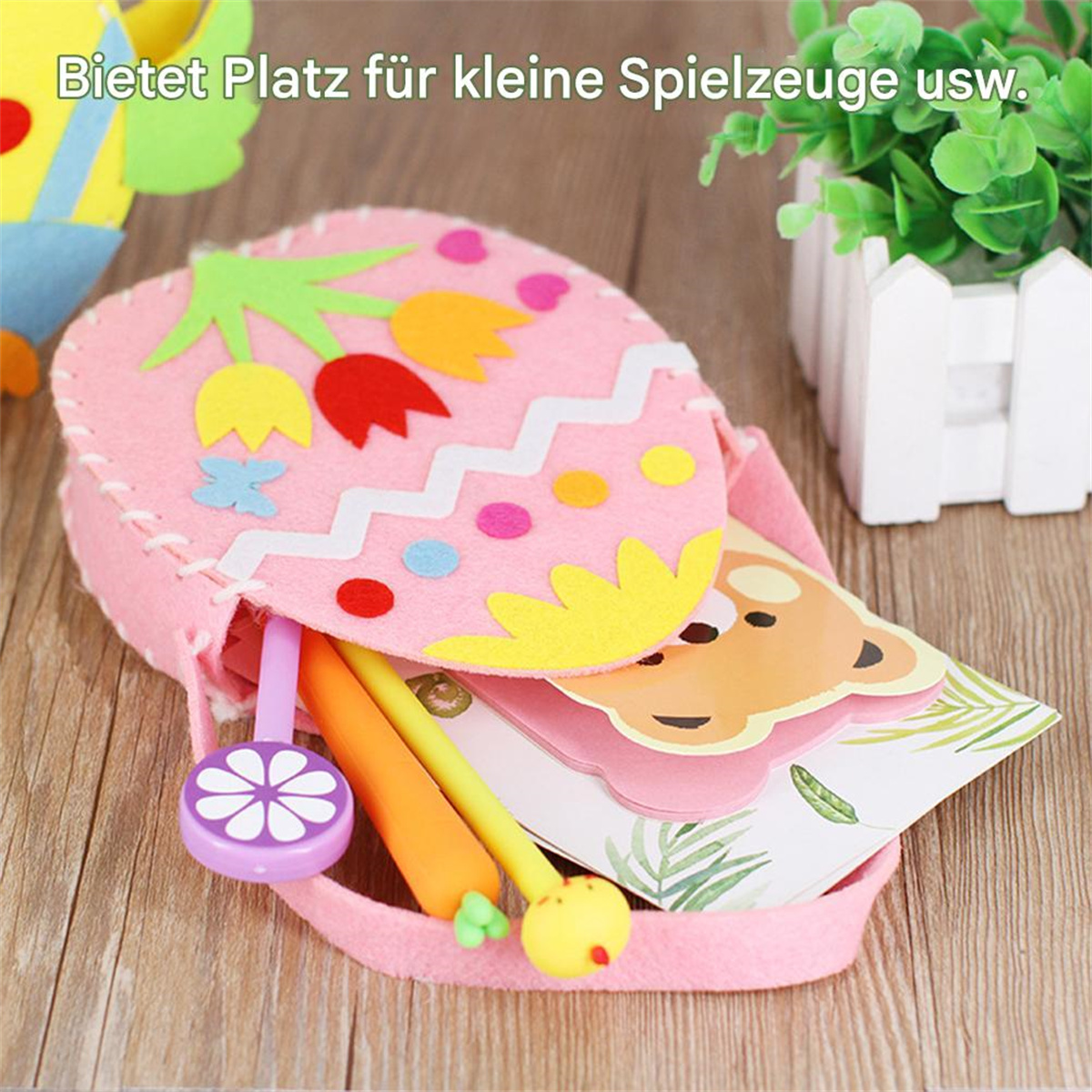 Eine rosa Osterei-förmige Tasche mit Schreibwaren, einschließlich Stiften und einer Karte.