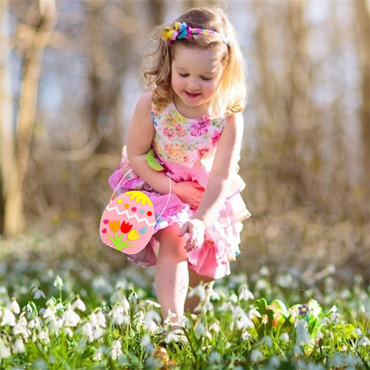 Junges Mädchen in Blumenkleid trägt Ostereier-Tasche auf Blumenwiese.