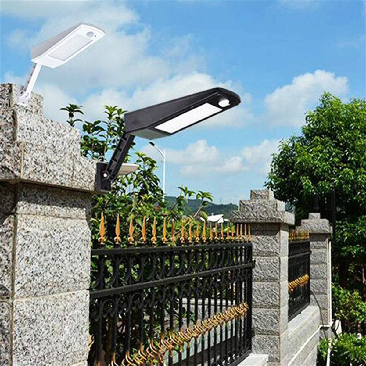 Zwei schwarze LED-Leuchten auf einem Steenzaun, mit blauem Himmel im Hintergrund.