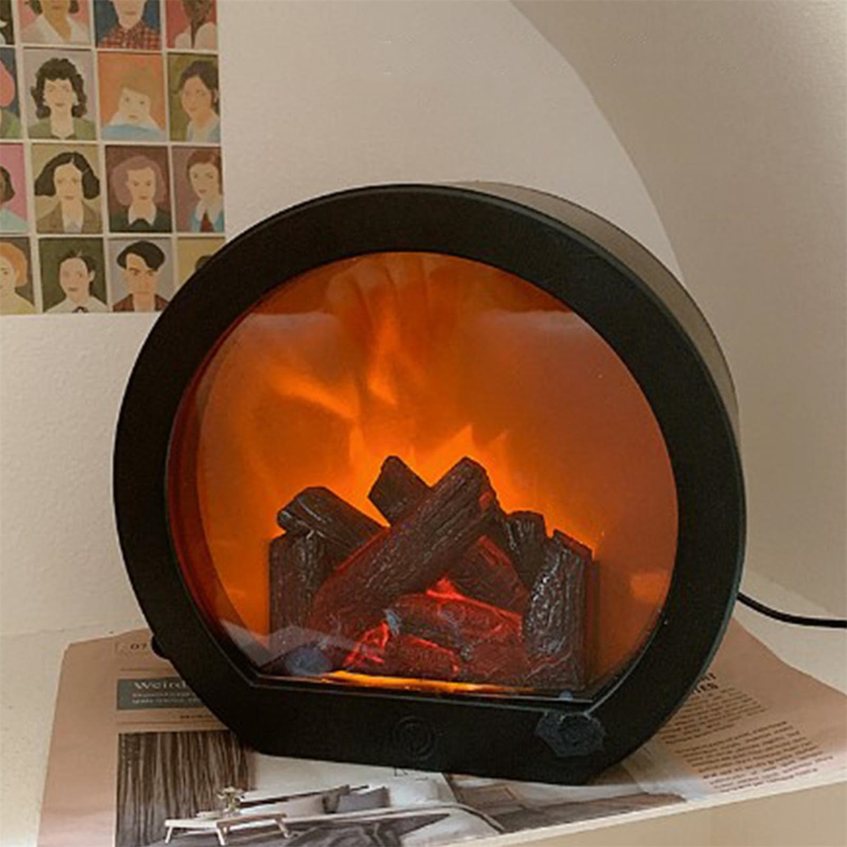 Ein schwarzer, runder elektrischer Kamin mit flammender Darstellung von brennendem Holz und einem schwarzen Rahmen, der auf einer Oberfläche steht.