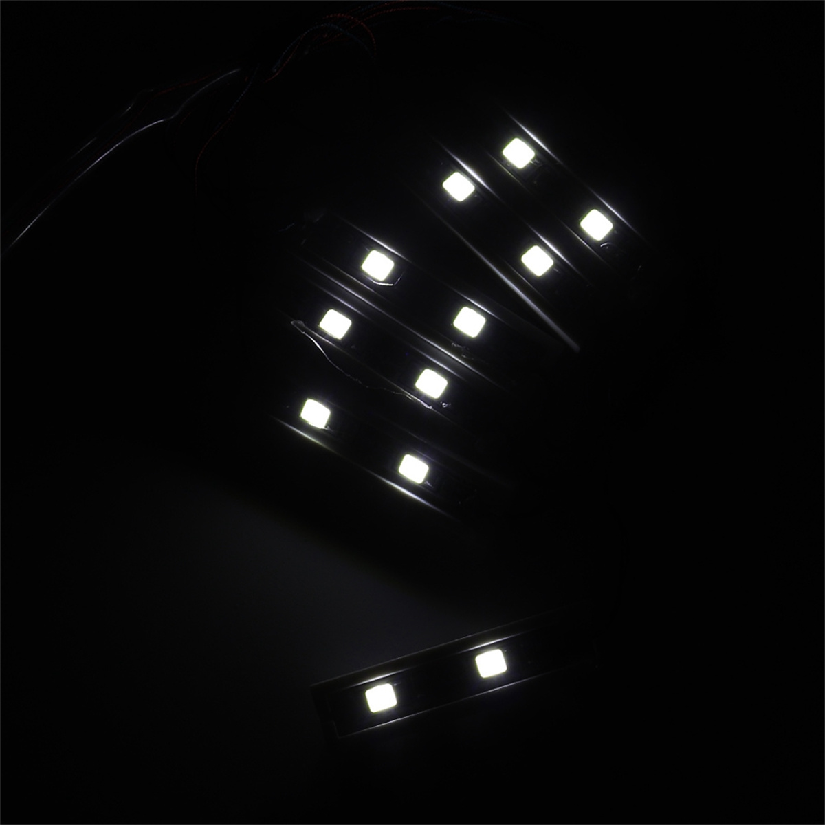 Dunkles Bild mit mehreren weißen LED-Lichtleisten, die Licht vor schwarzem Hintergrund aussenden.