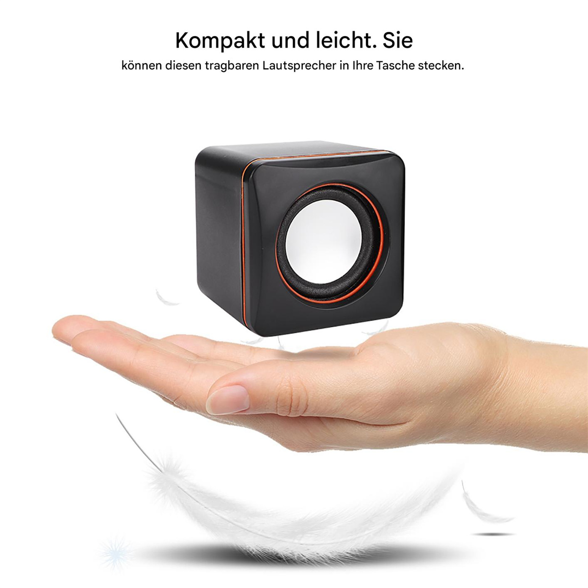 Schwarzer Würfel-Lautsprecher auf Hand, orangefarbener Rand, weißer Lautsprecher. Weißer Hintergrund. Federn.