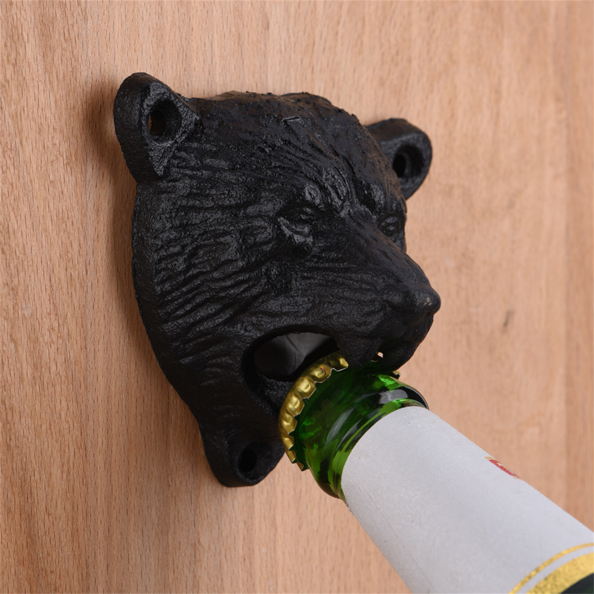Schwarzer Bärenkopf-Flaschenöffner auf Holzoberfläche, der eine Bierflasche öffnet.