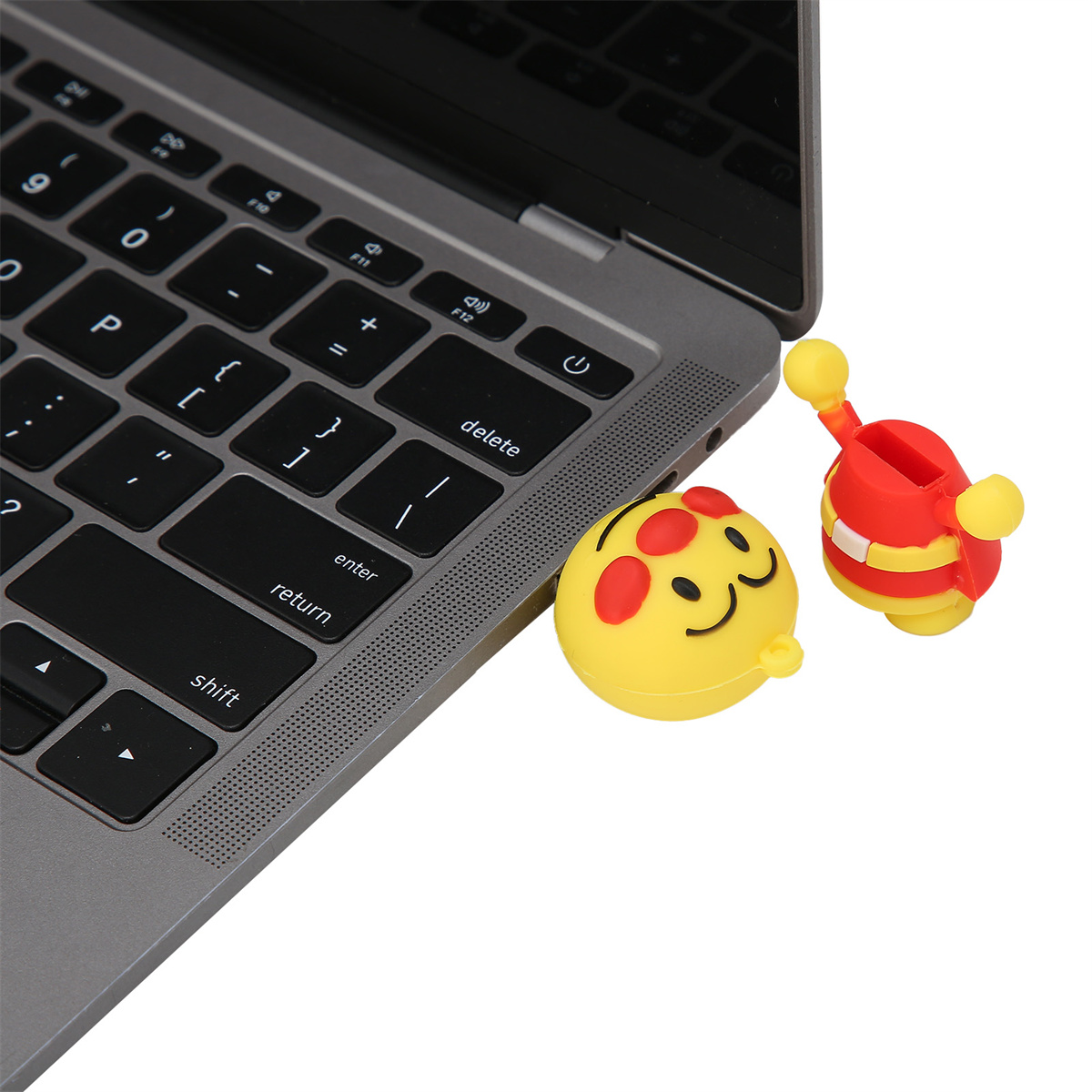 Laptop-Tastatur mit zwei USB-Flash-Laufwerken, einem Smiley-Gesicht und einer roten und gelben Cartoon-Biene.