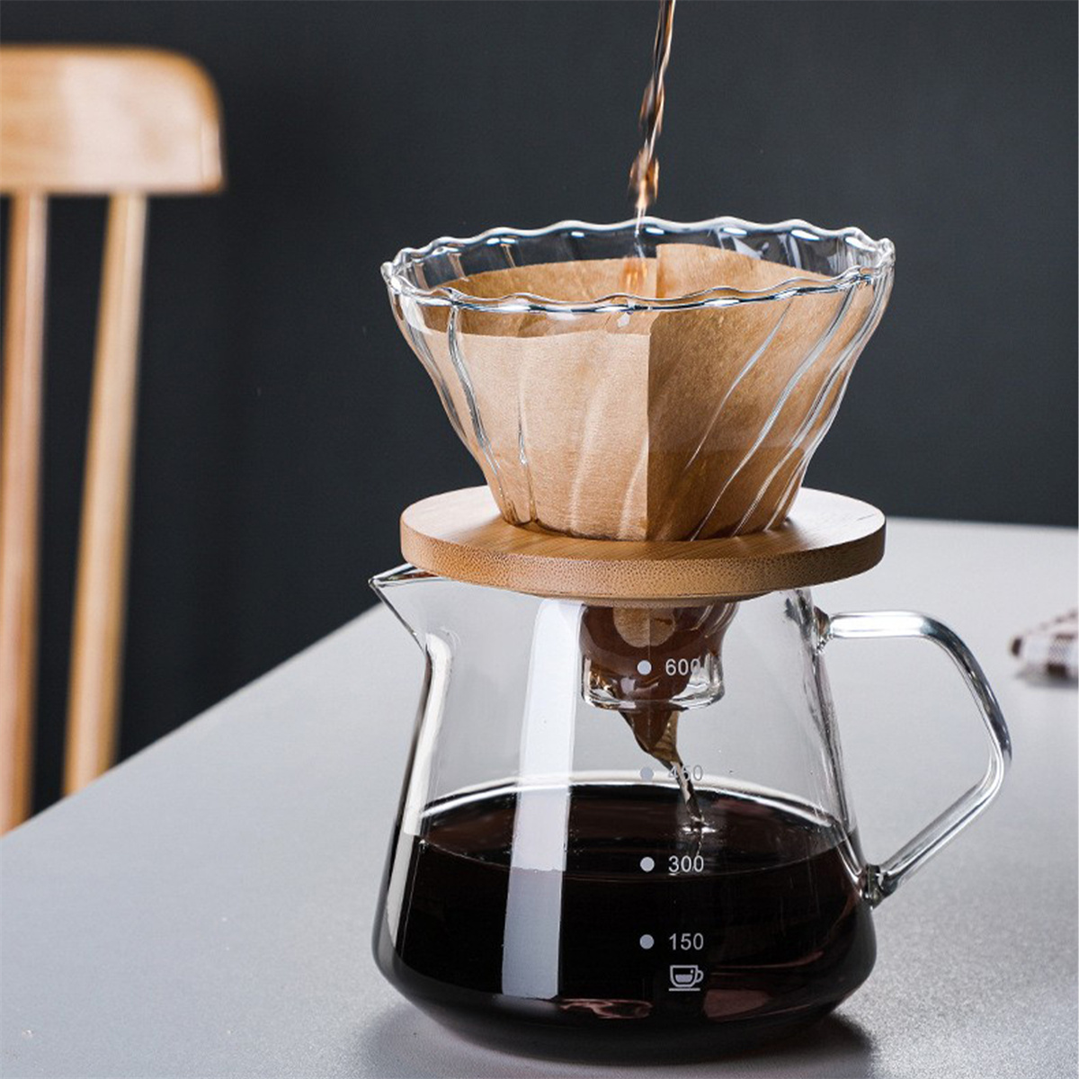 Kaffeezubereitung. Glaskaraffe, Holzsockel, Papierfilter. Kaffee wird von oben gegossen.