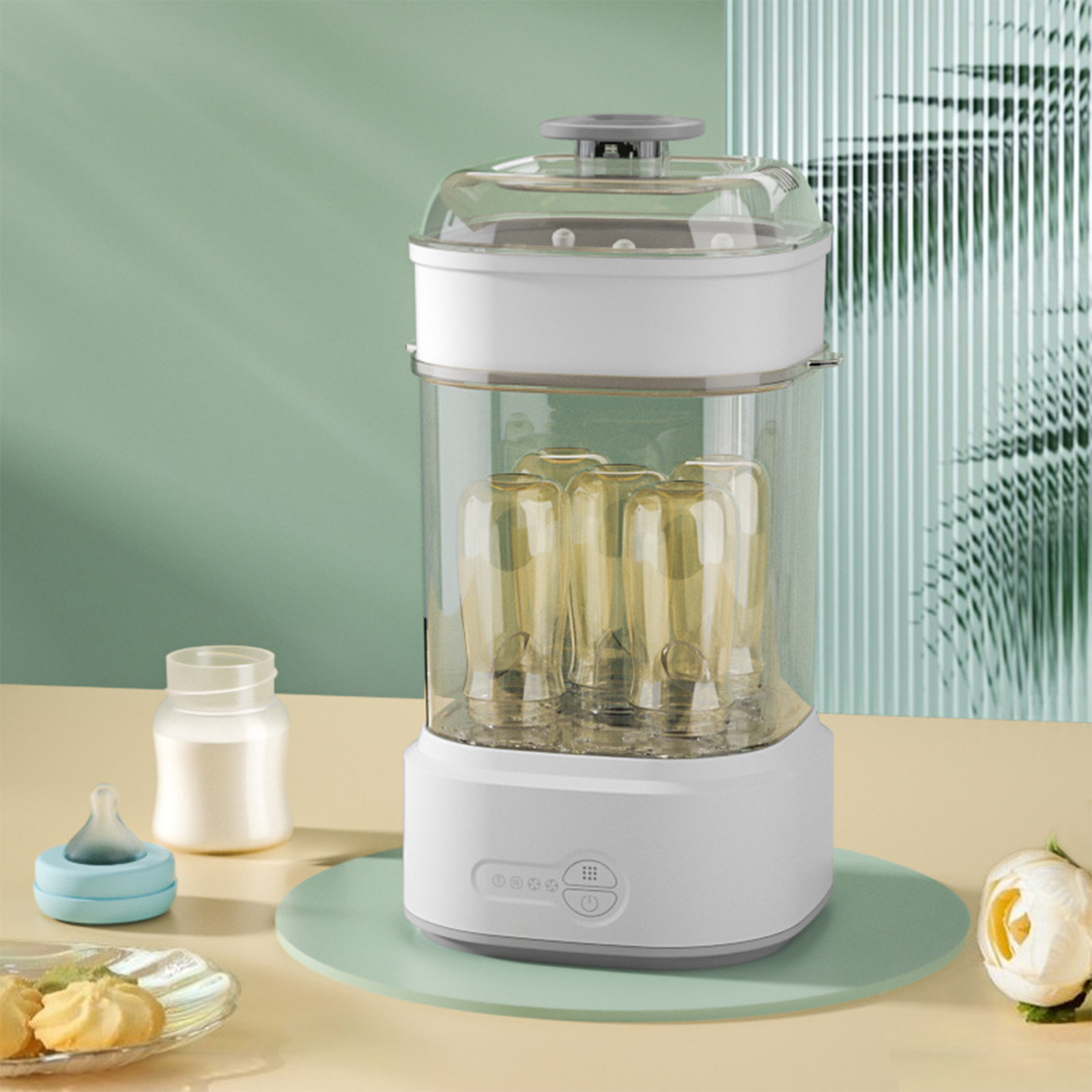 Ein weißer Babyflaschensterilisator mit Flaschen darin. Er steht auf einer hellgrünen Matte, mit einer kleinen Flasche und einem Snack.