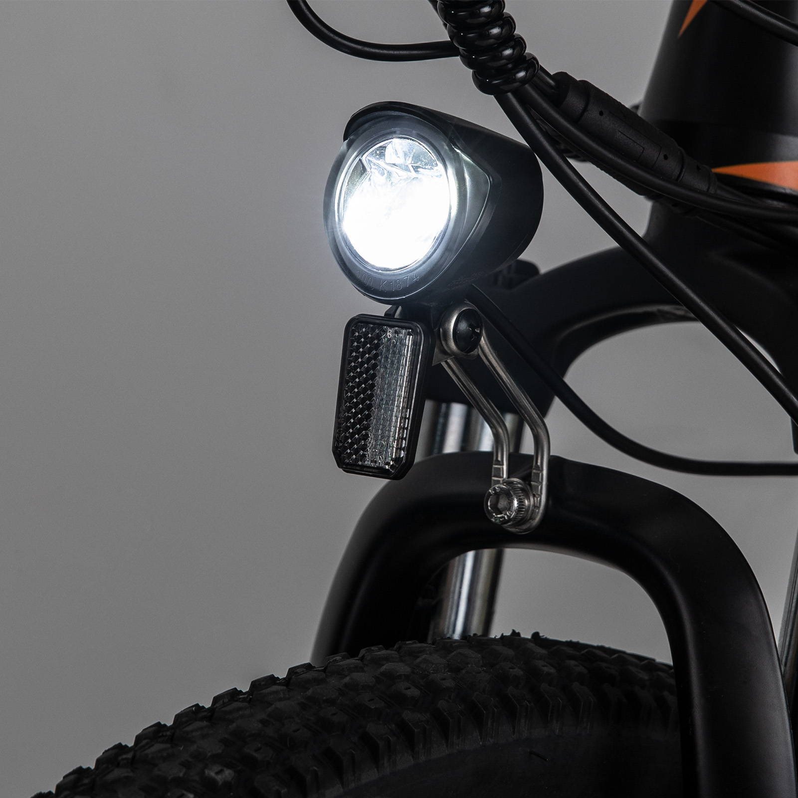 Nahaufnahme eines Fahrradscheinwerfers und Reflektors an einem Fahrrad. Der Scheinwerfer ist hellweiß.
