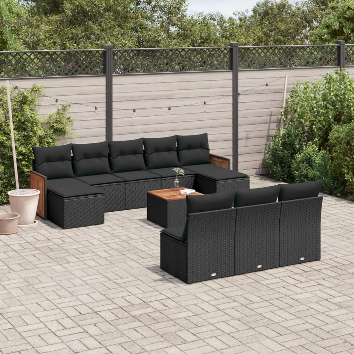 Outdoor-Möbelset aus schwarzem Korbgeflecht mit schwarzen Kissen auf einer Steinterrasse.