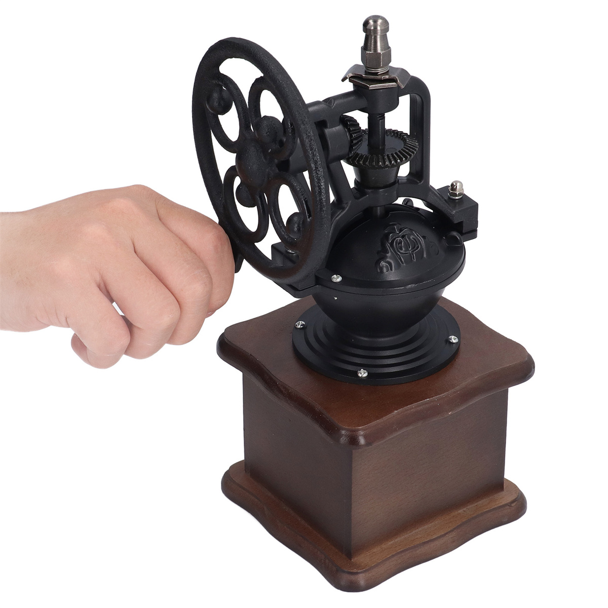 Hand dreht eine schwarze manuelle Kaffeemühle mit Holzsockel. Weißer Hintergrund.