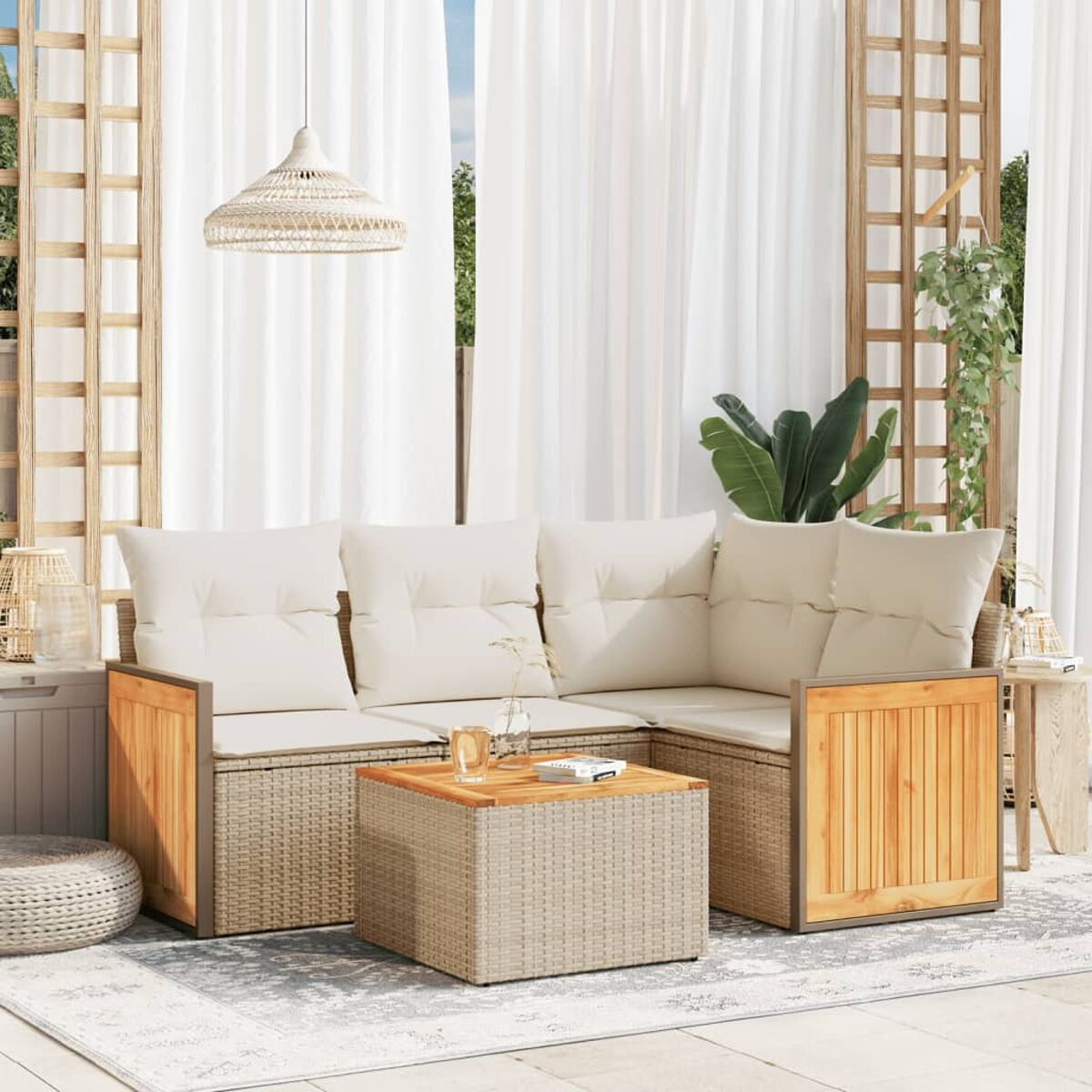 Set patio esterno con divano, tavolo e tappeto. Tende bianche e traliccio in legno sullo sfondo.