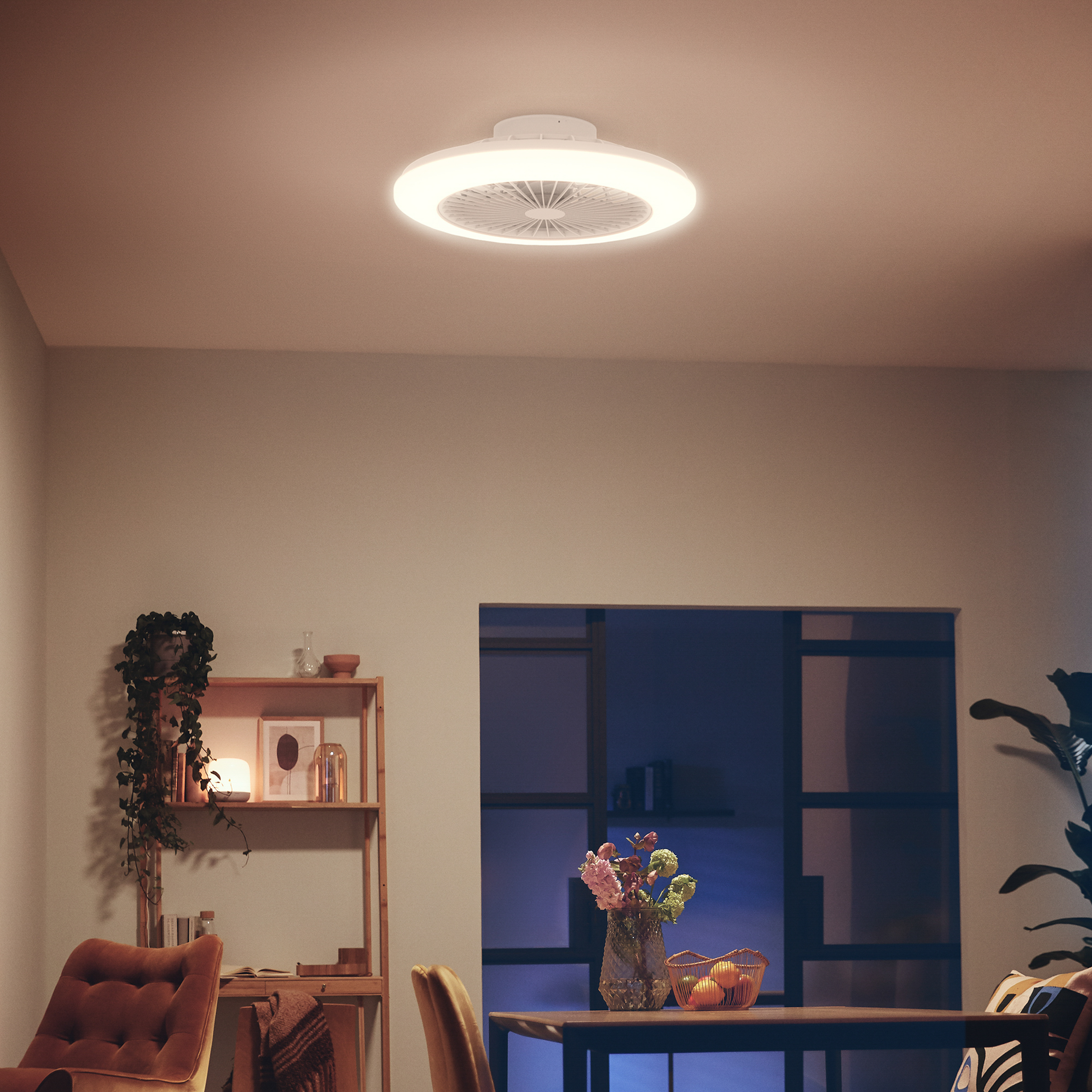 Un intérieur moderne avec une lumière de ventilateur de plafond. Une table avec des fleurs et une fenêtre en arrière-plan.