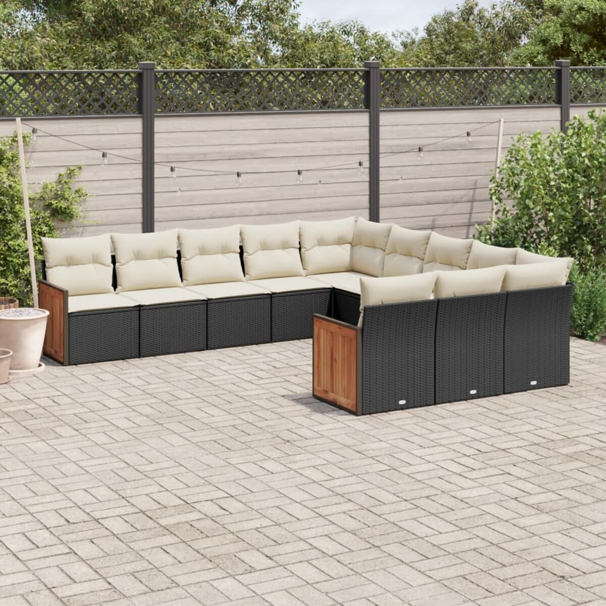 Divano angolare da esterno, vimini nero, cuscini beige, accenti in legno e sfondo patio in mattoni.