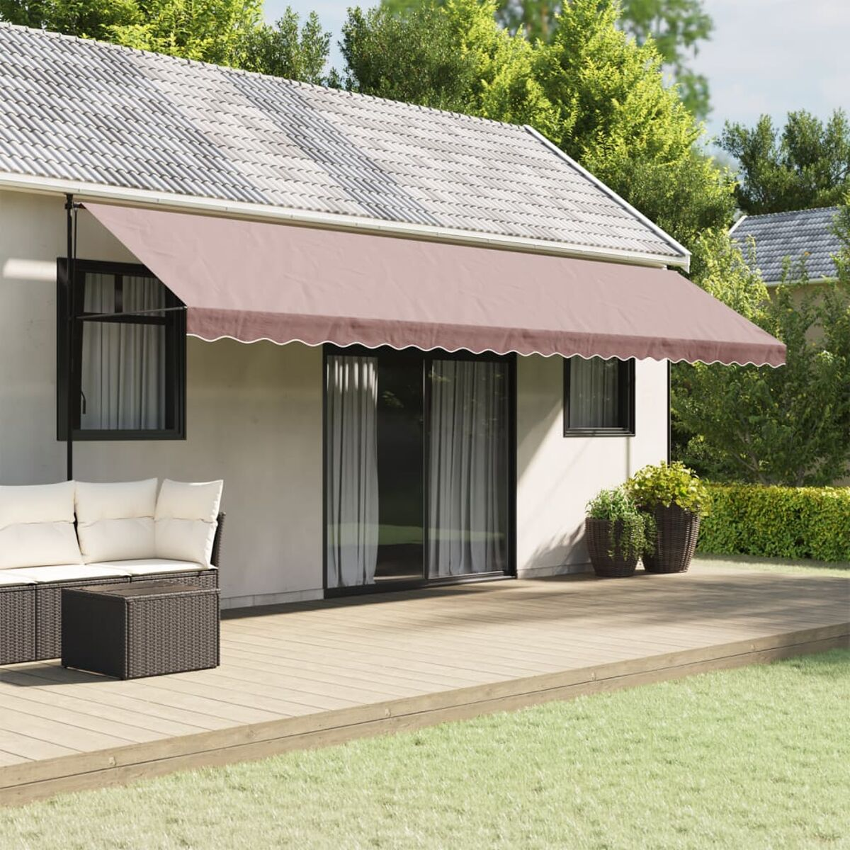 Casa con tenda da sole marrone sopra una porta e due finestre. Terrazza in legno e piante in primo piano.