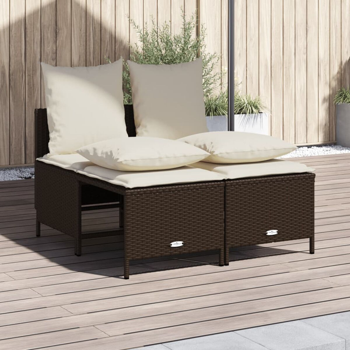 Zwei braune Korbstühle mit weißen Kissen stehen auf einer Holzterrasse.