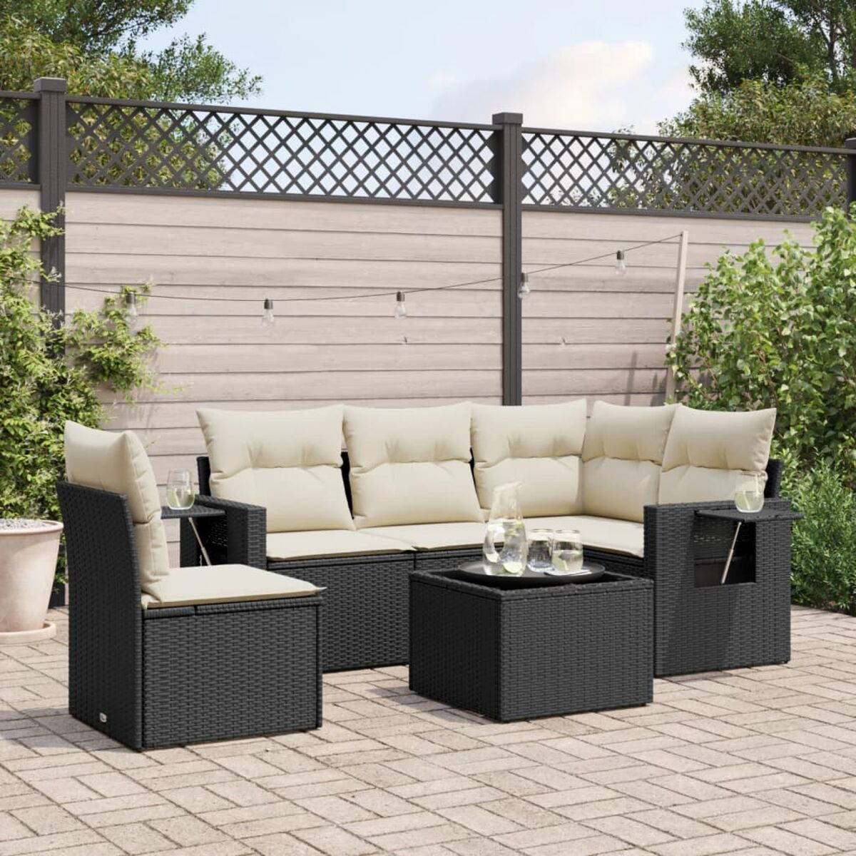 Set di mobili da patio: divano nero intrecciato, poltrona e tavolino con cuscini.
