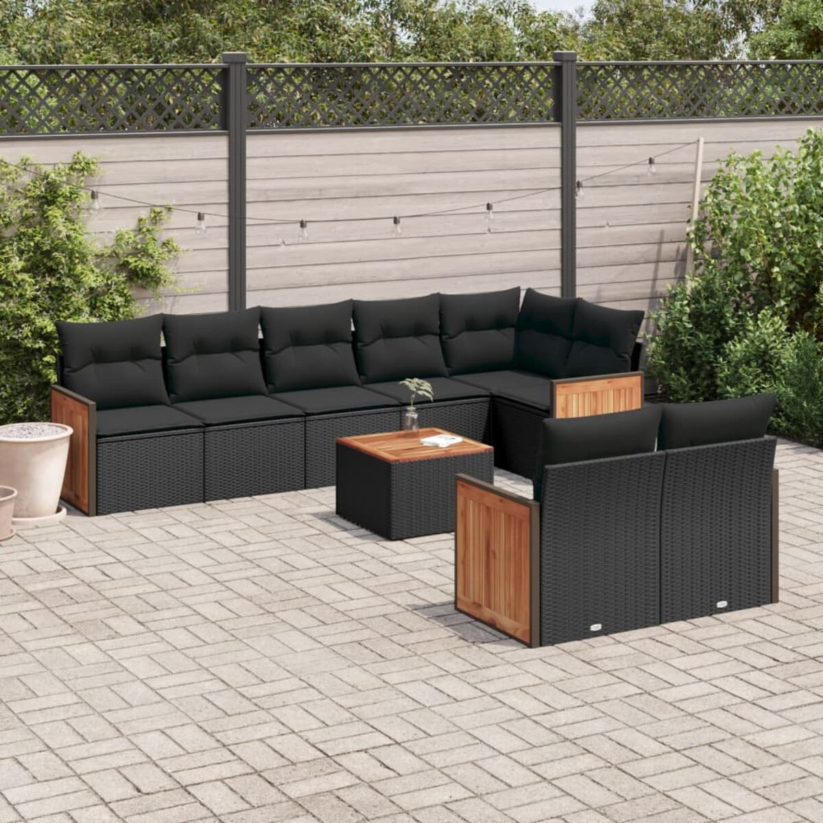 Schwarzes Outdoor-Korbmöbel-Set mit Holzakzenten, Kissen und Tisch. Auf einer Ziegelterrasse.