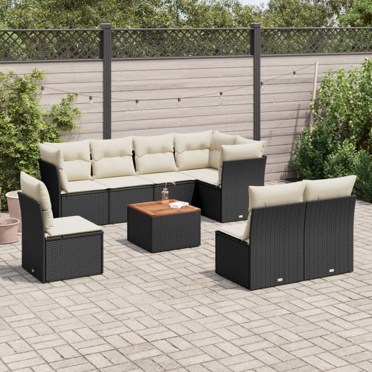 Outdoor-Möbelset aus schwarzem Rattan. Enthält ein Ecksofa, einen Couchtisch und zwei Stühle. Der Hintergrund ist eine Terrasse.