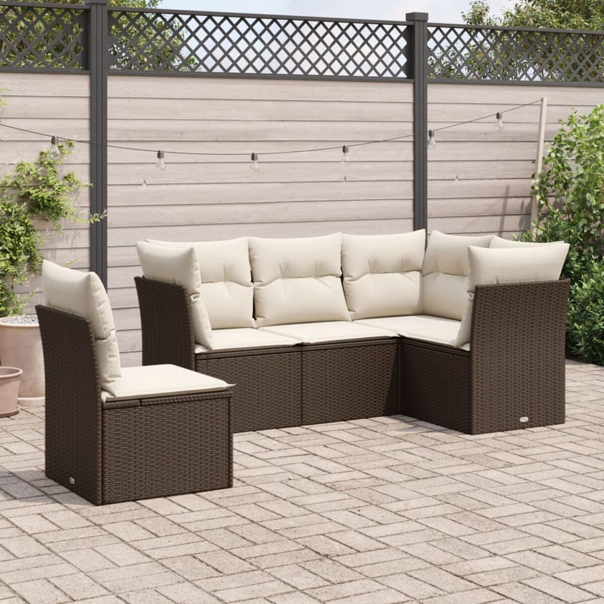 Gartenmöbel-Set, braunes Wicker mit cremefarbenen Kissen, auf einer Ziegelterrasse, mit Holzzaun.
