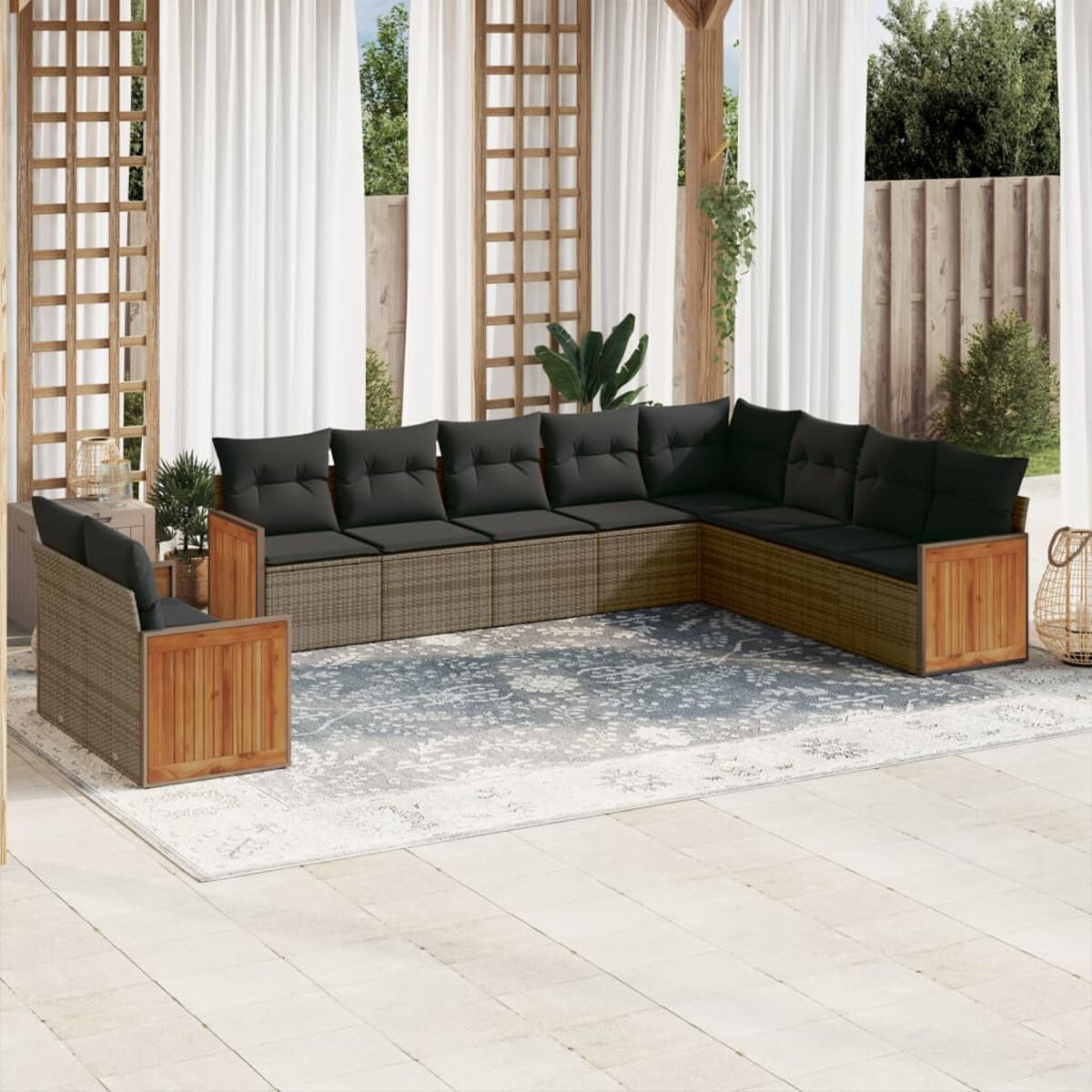 Divano componibile da esterno con cuscini grigio scuro. Un tappeto bianco è su un patio in pietra.