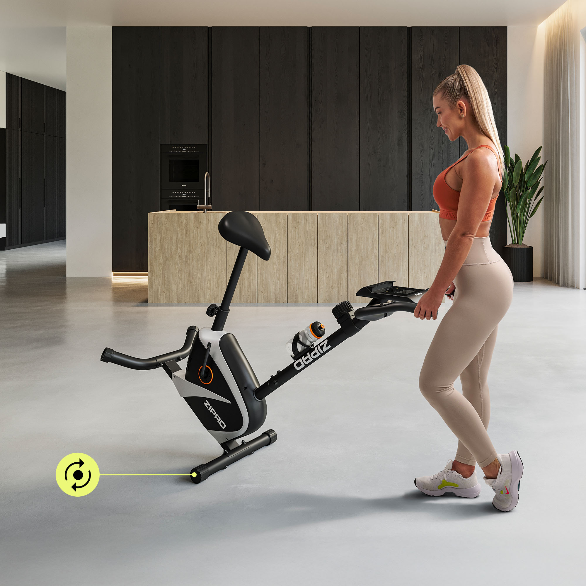 Eine Frau benutzt ein stationäres Trainingsfahrrad. Das Fahrrad ist schwarz-weiß. Die Frau trägt Sportkleidung.