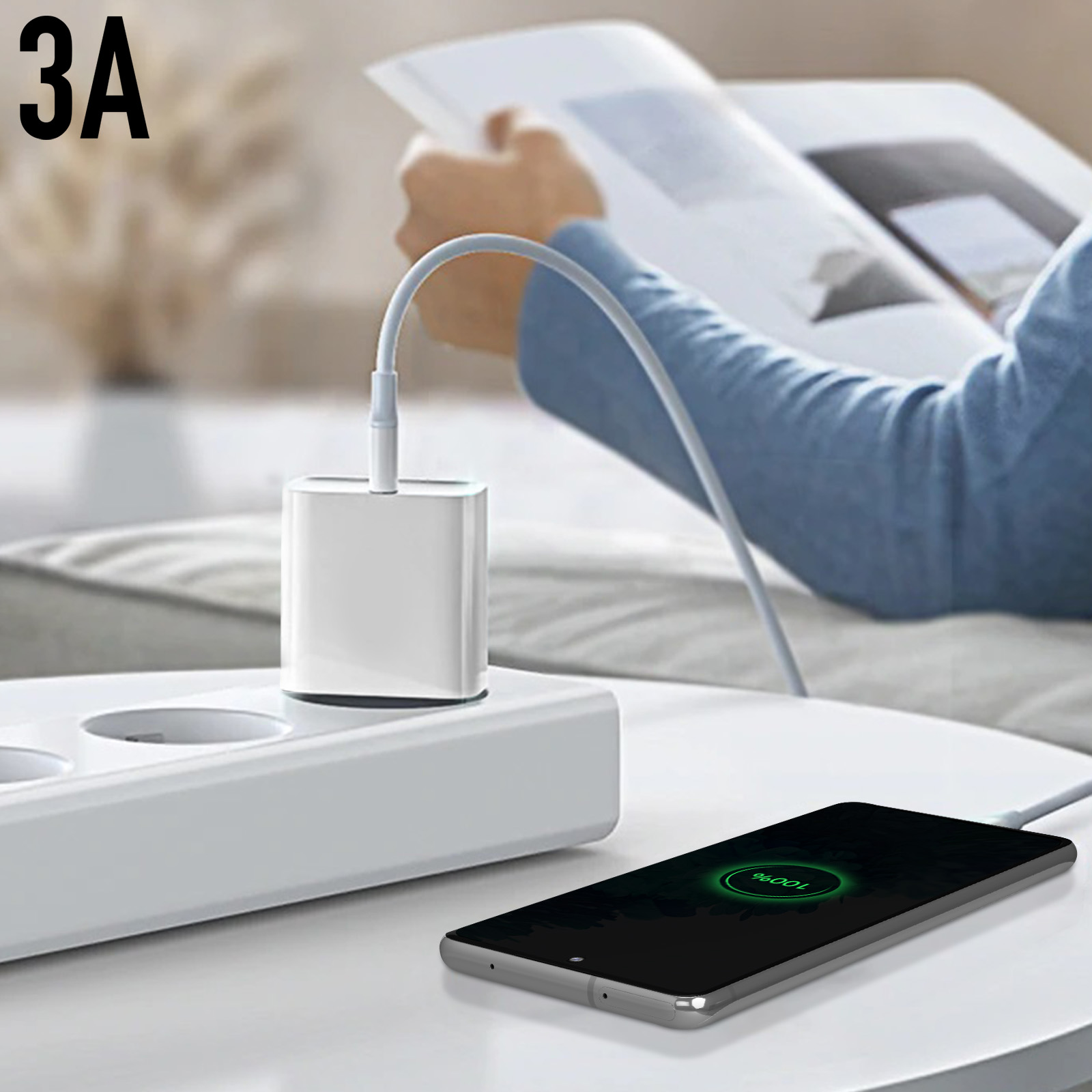 Un telefono in carica con un caricabatterie bianco collegato a una presa. Una persona legge.