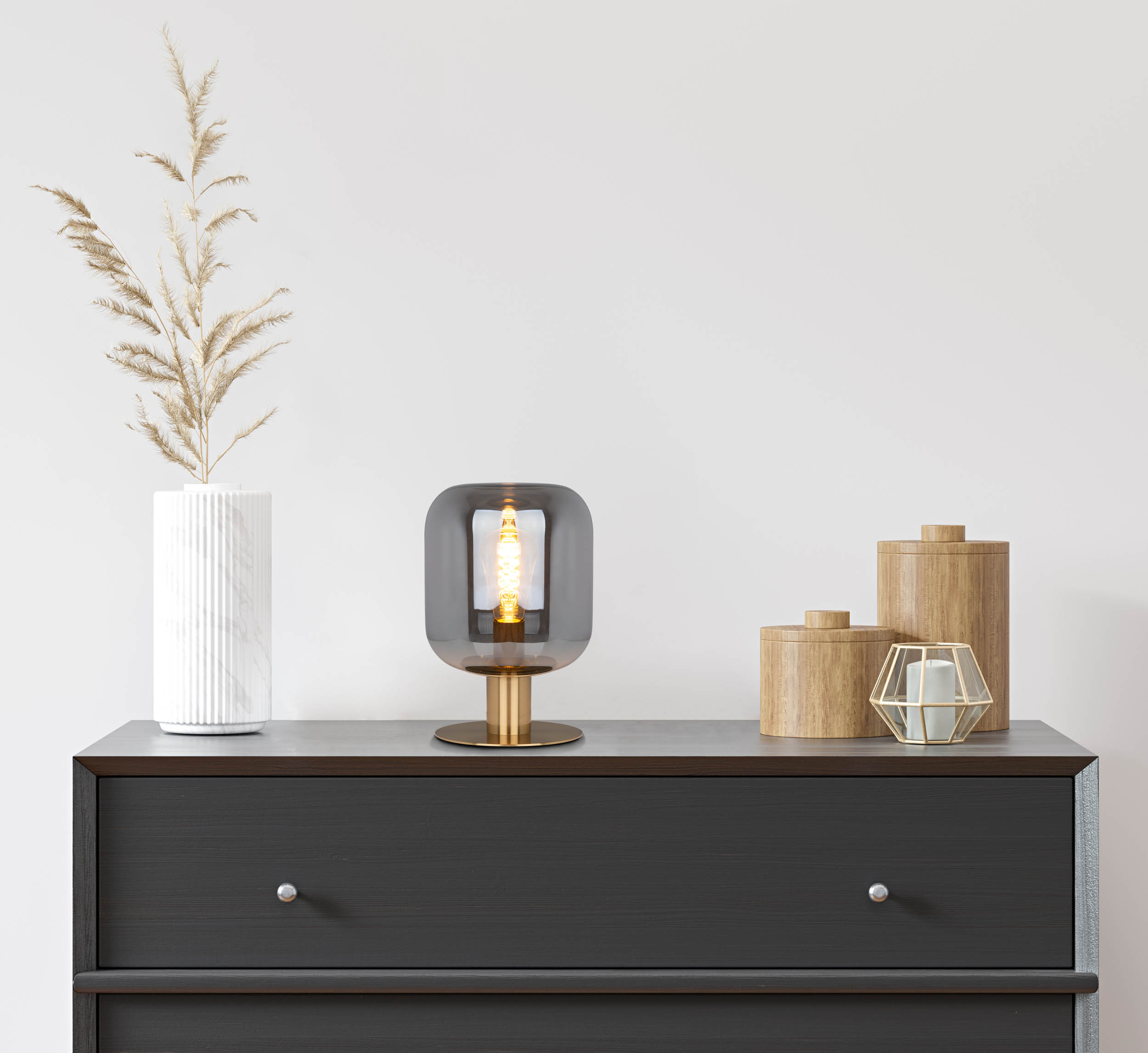 Tischlampe mit Glühbirne in einer Kommode. Vase und Holzkisten sind ebenfalls sichtbar.