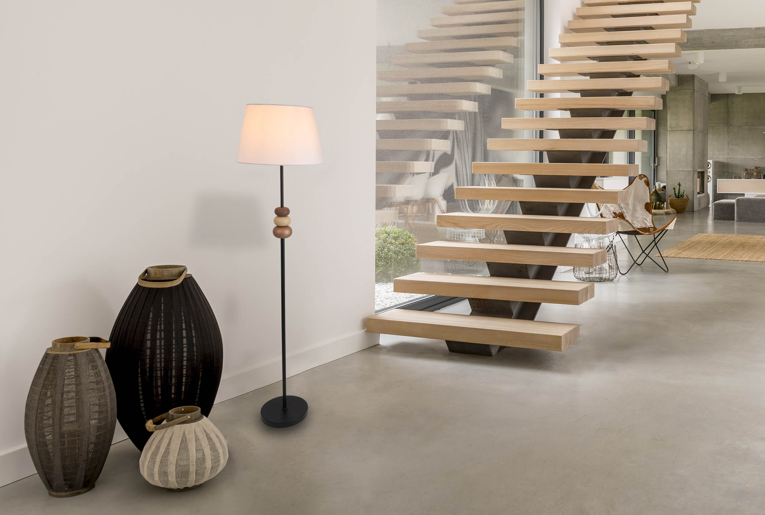 Innenszene mit Stehlampe, Vasen und Treppe. Die Lampe hat einen weißen Schirm.