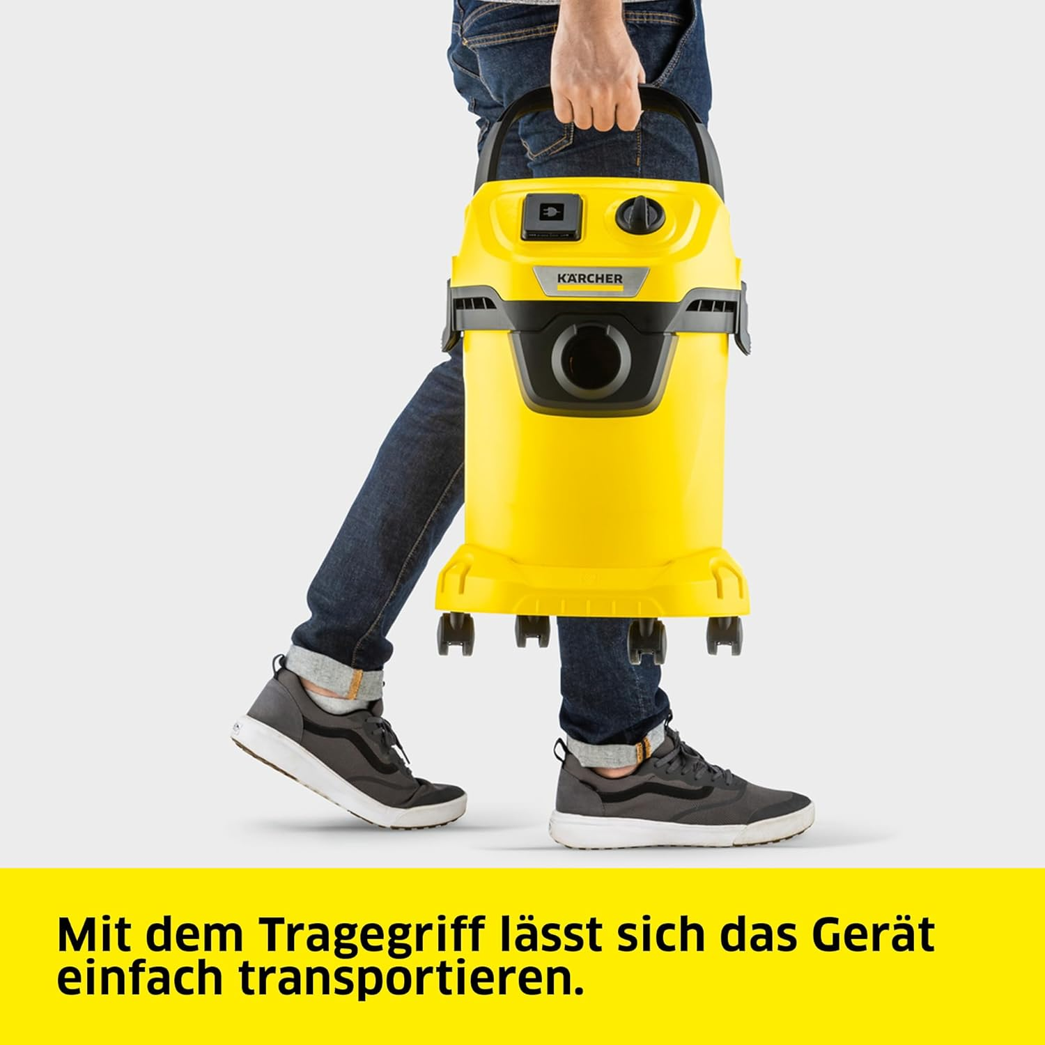 Eine Person, die einen gelben Staubsauger mit Rädern hält.