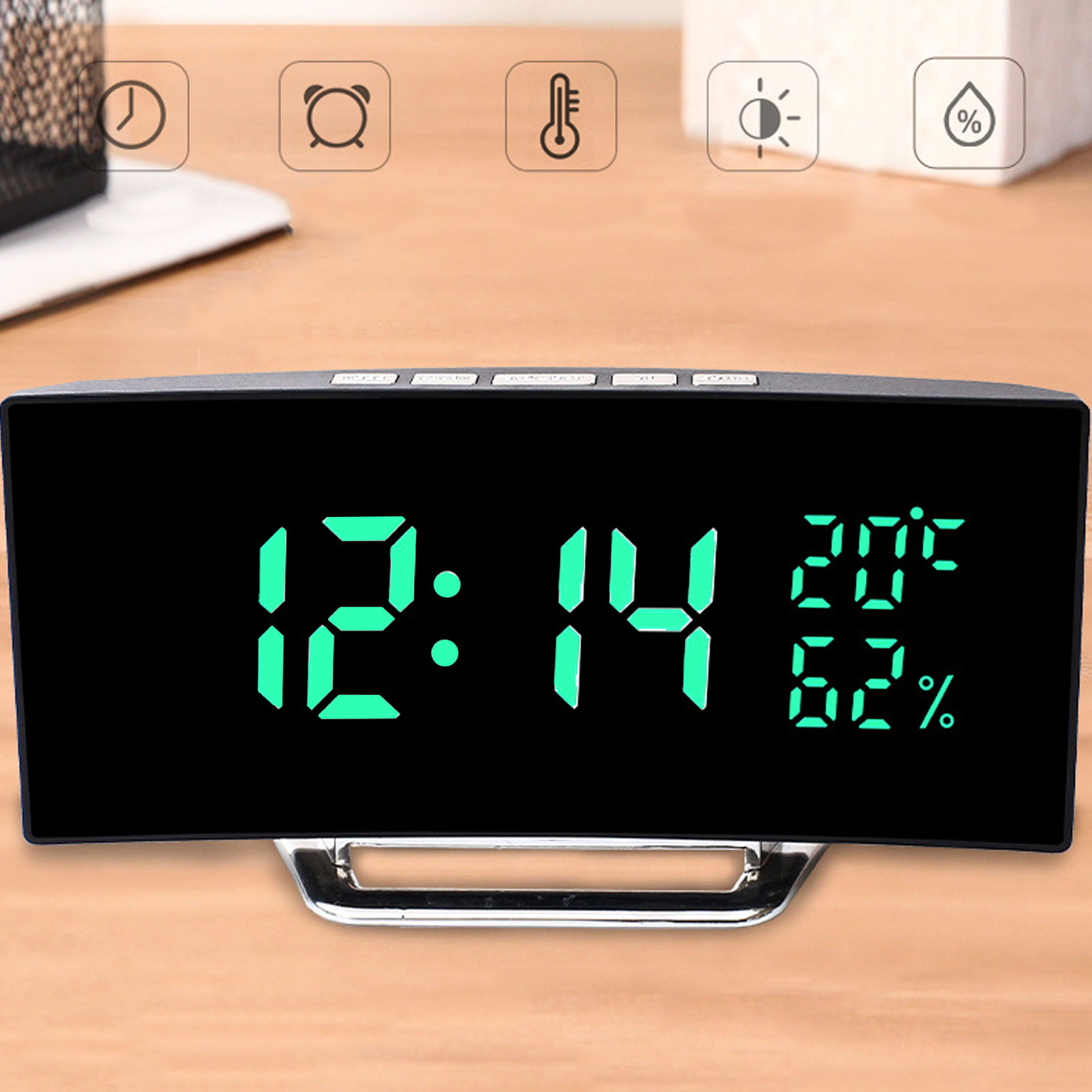 Eine schwarze Digitaluhr mit grünen Ziffern zeigt Zeit, Temperatur und Luftfeuchtigkeit auf einem Schreibtisch.