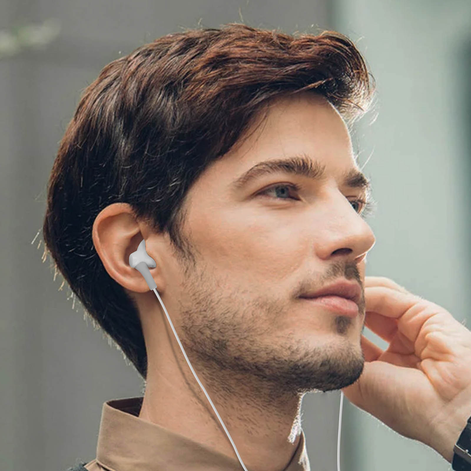 Un hombre con auriculares grises, perfil lateral. El hombre tiene cabello castaño y barba.