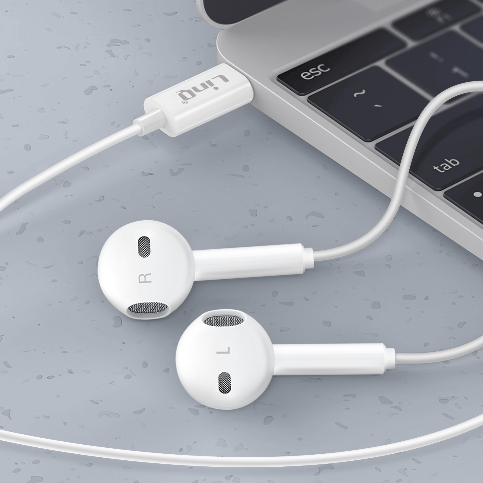 Auricolari cablati bianchi collegati a un laptop. Gli auricolari sono contrassegnati con 'L' e 'R'.