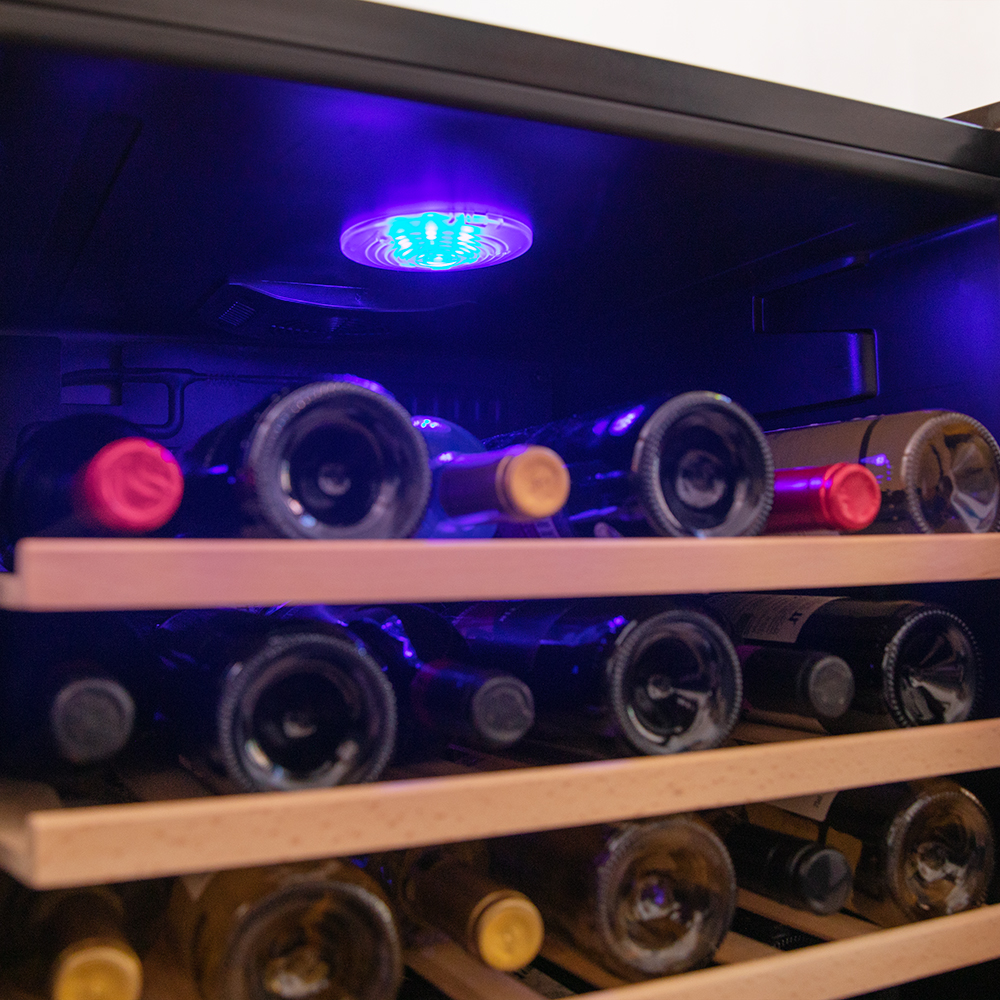Bottiglie di vino su scaffali di legno in un frigorifero, illuminate da una luce blu.