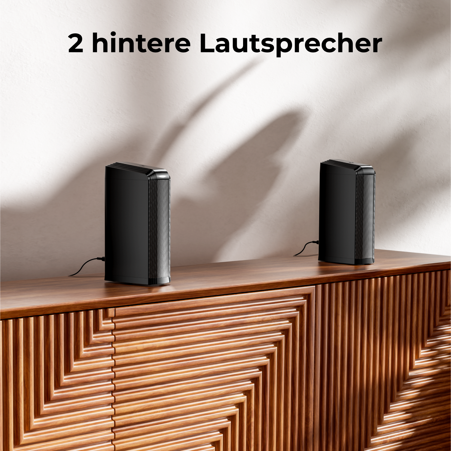 Zwei schwarze Lautsprecher auf einem Holzschrank. Text: 2 hintere Lautsprecher.