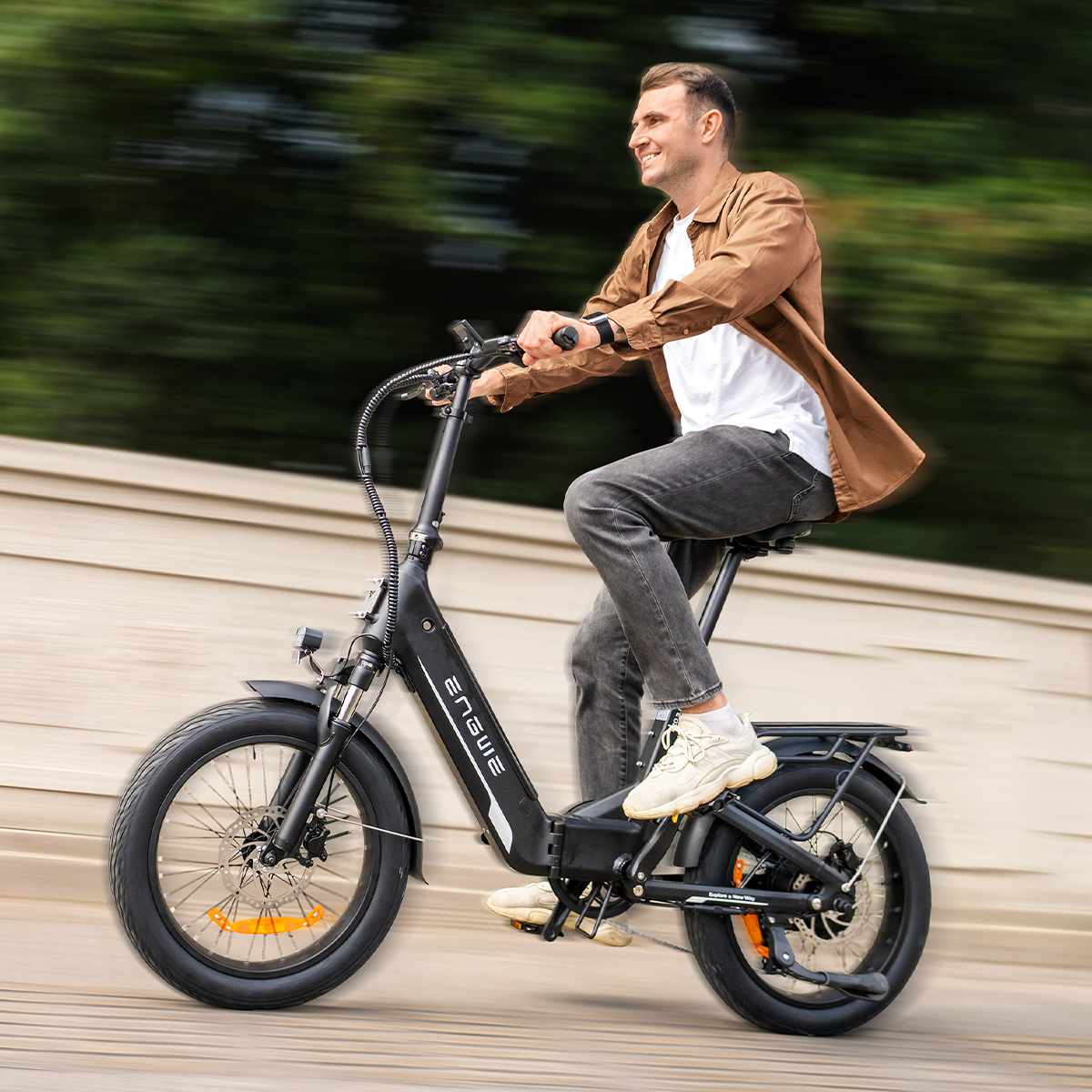 Un uomo che guida una bici elettrica all'aperto, sorridendo e in movimento.