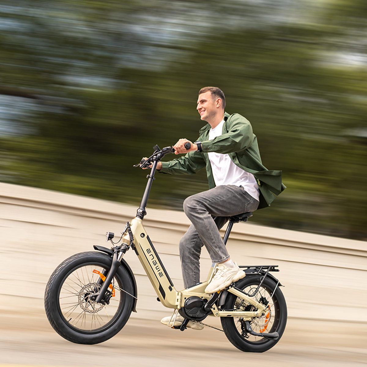 Uomo in sella a una e-bike su sfondo sfocato. La bici ha un telaio beige.