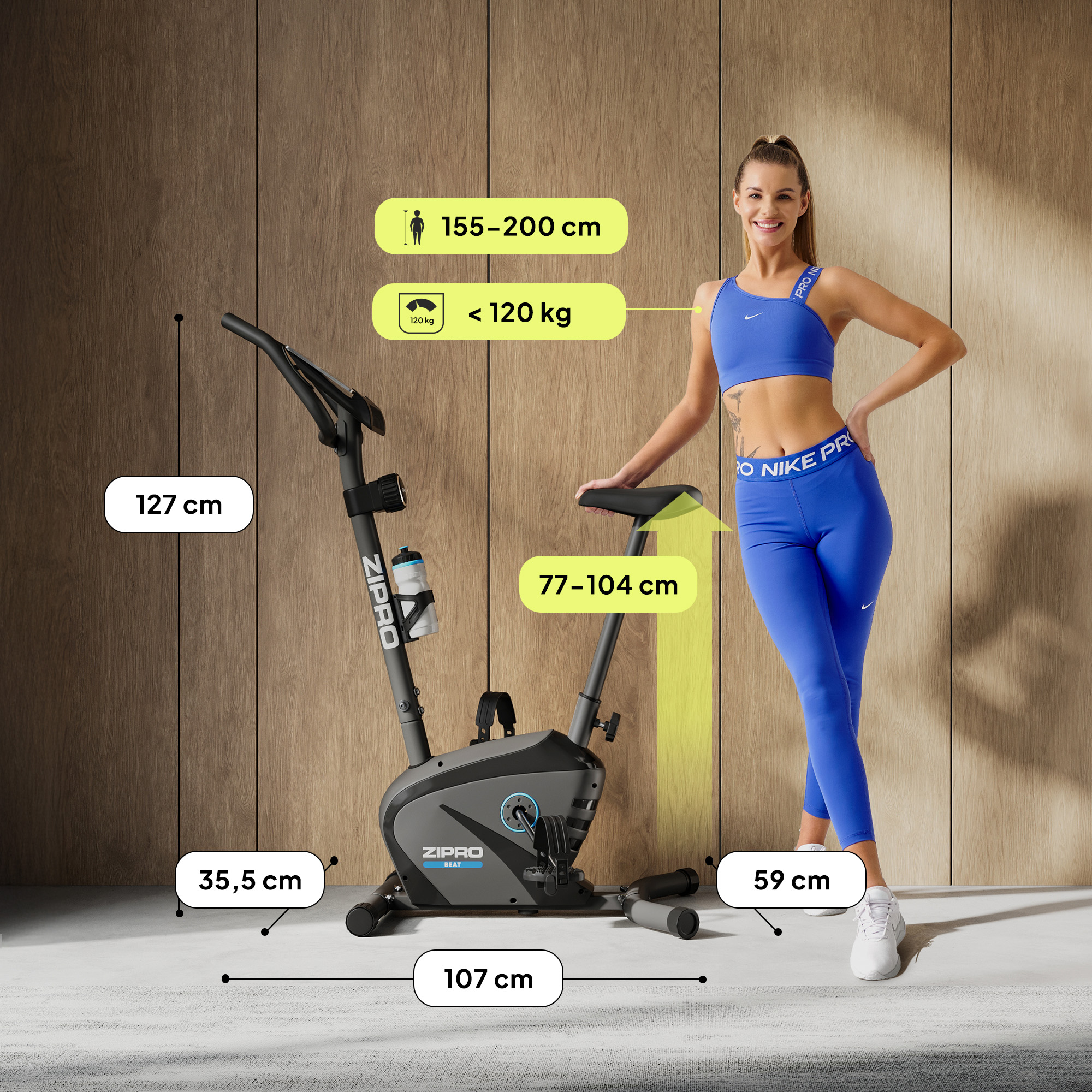 Frau neben einem schwarzen Heimtrainer. Abmessungen werden gezeigt. Höhe von 155-200cm und Gewichtsgrenze <lt/>120kg.