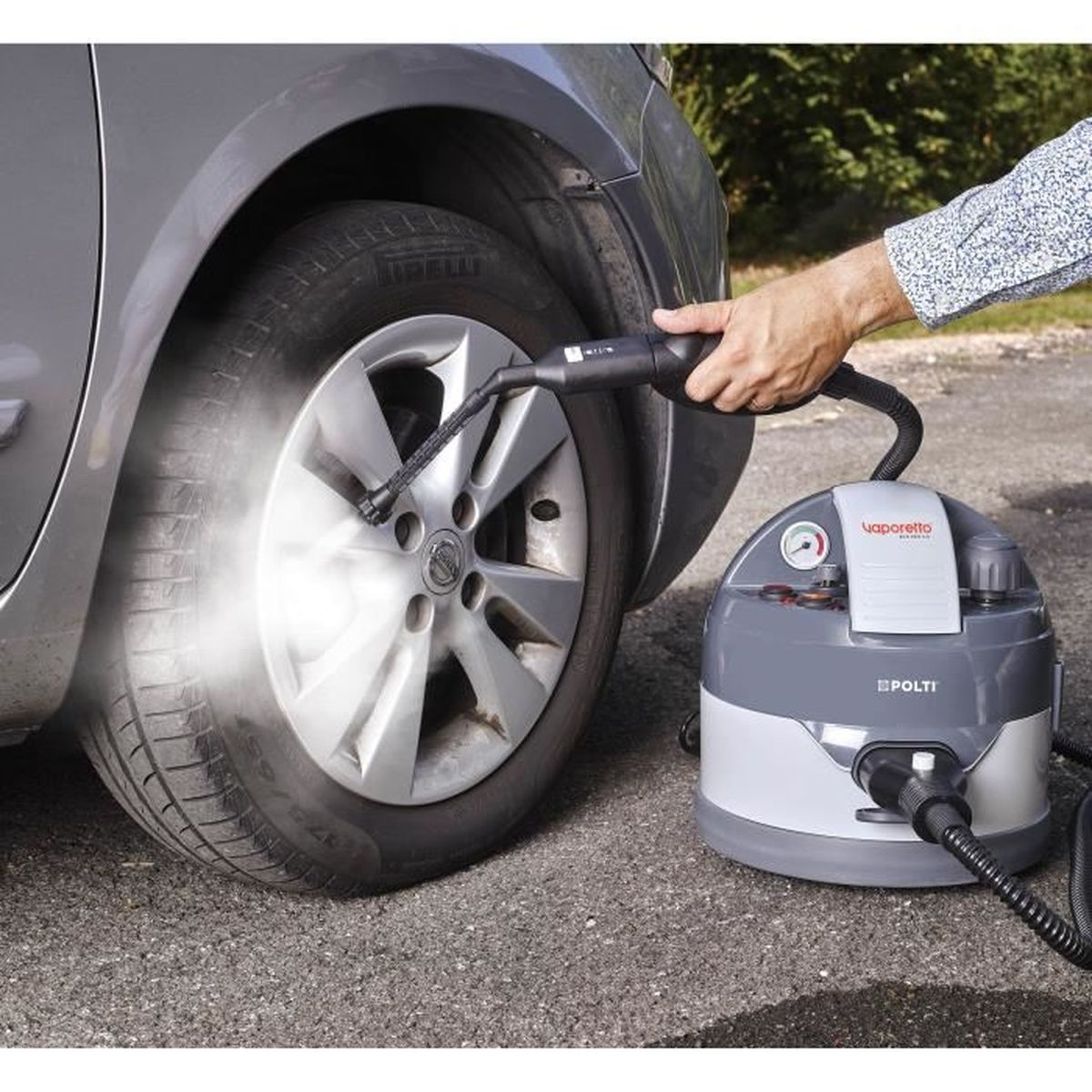 Osoba używająca myjki parowej do opony samochodowej. Widoczna szaro-biała myjka parowa.