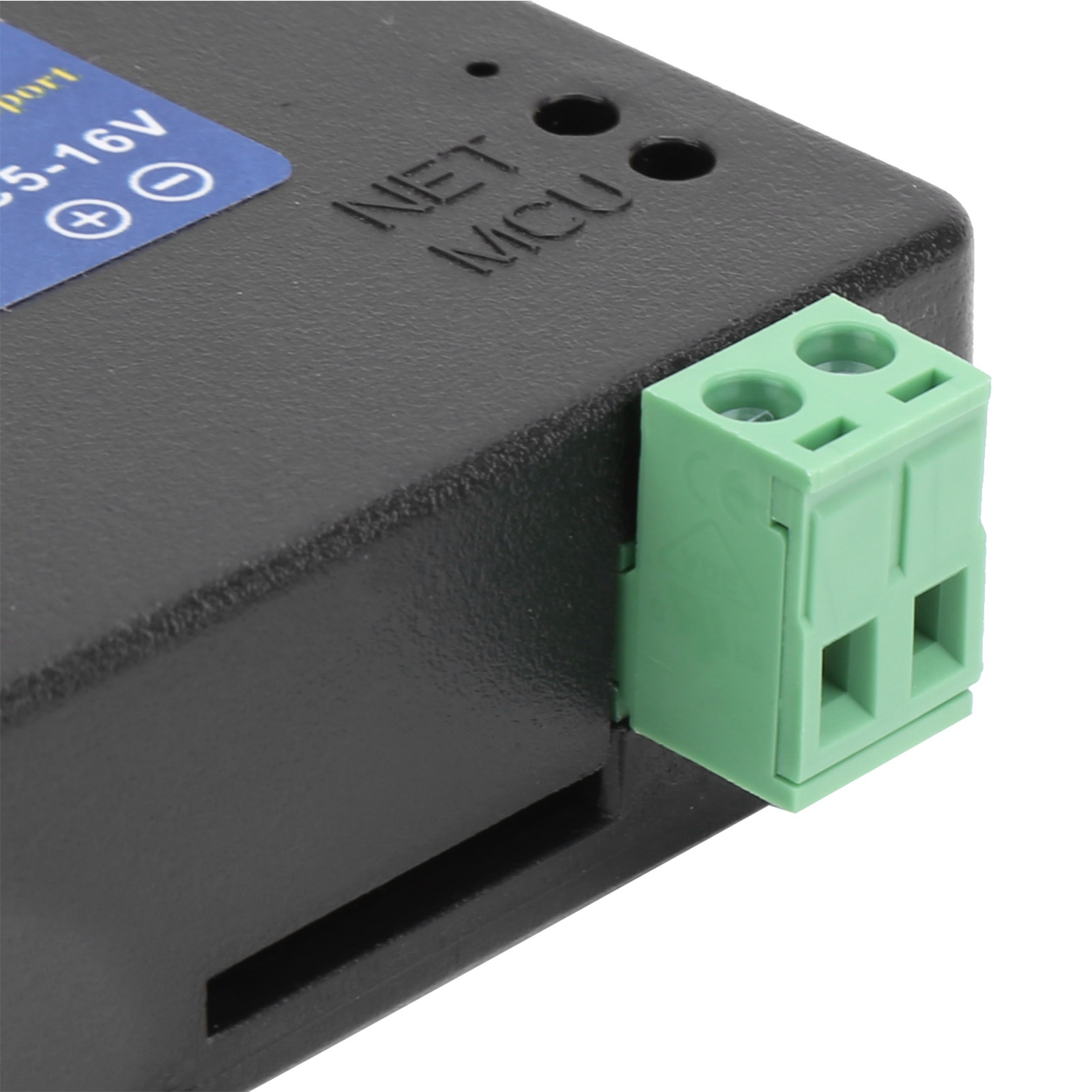 Schwarze elektronische Komponente. Sie hat grüne Anschlüsse und ein blaues Etikett mit Text und Symbolen.
