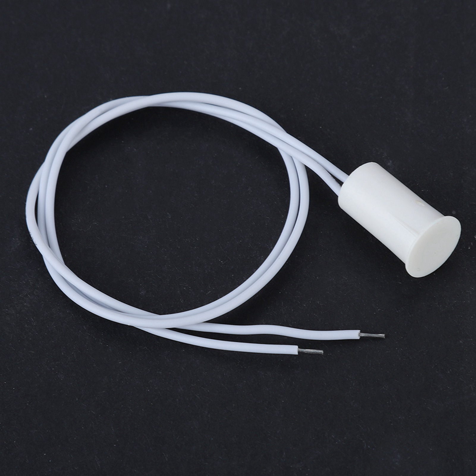 Weißer zylindrischer Türsensor mit Drähten, auf schwarzem Hintergrund. Der Sensor ist abgebildet.
