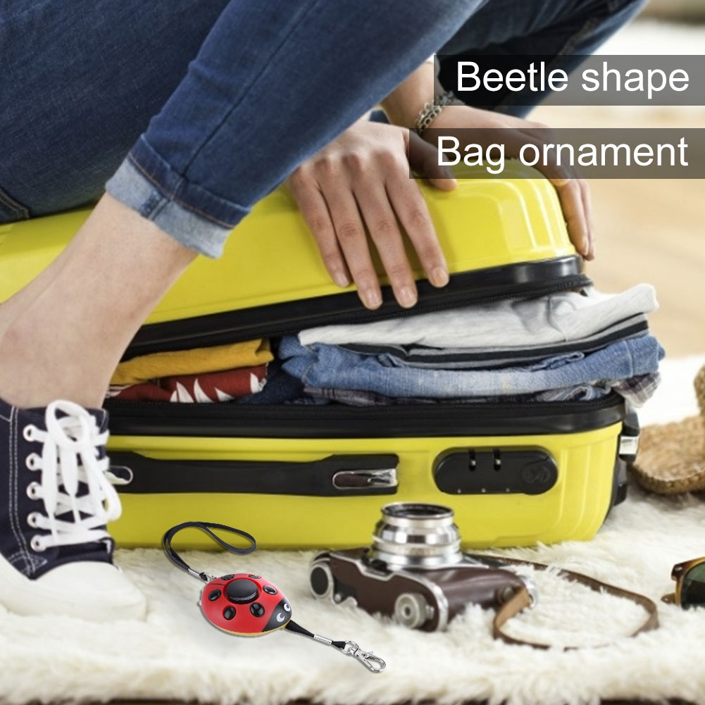 Eine Person packt einen gelben Koffer. Ein Marienkäfer-Taschenanhänger und eine Kamera sind sichtbar.