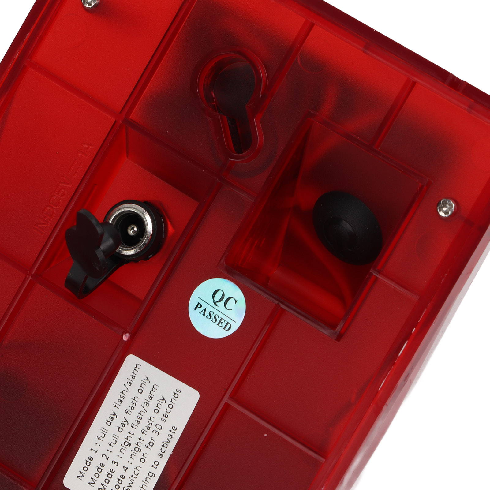 Die Unterseite eines roten elektronischen Geräts mit Stromeingang, einem QC Passed-Aufkleber und Schraubenlöchern.