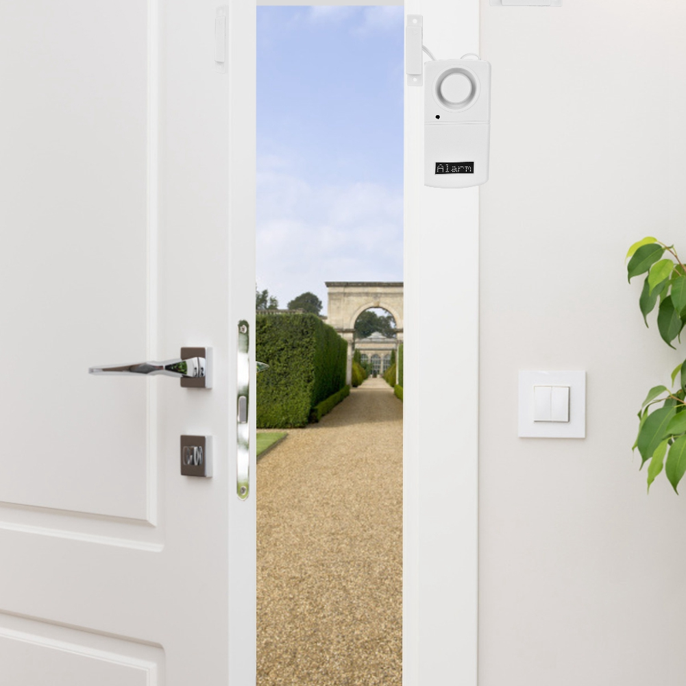 Weiße Tür mit Blick auf einen grünen Garten mit Kiesweg und einem Alarmsystem an der Wand.