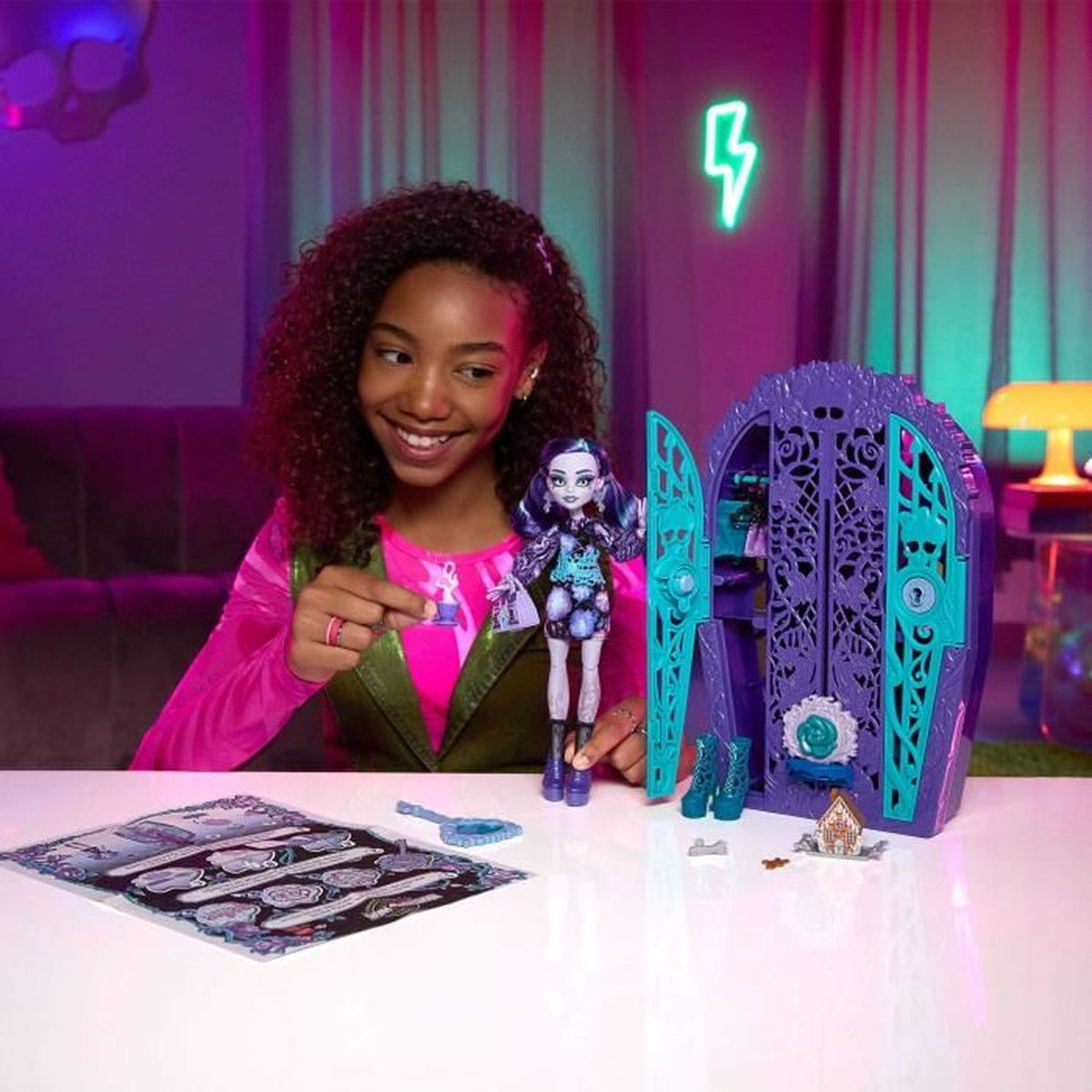Una niña con una muñeca y un juego. La muñeca y el juego son morados y turquesa.